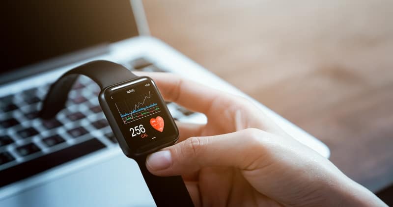 Close up of a hand touching a smartwatch with a health app on the screen.